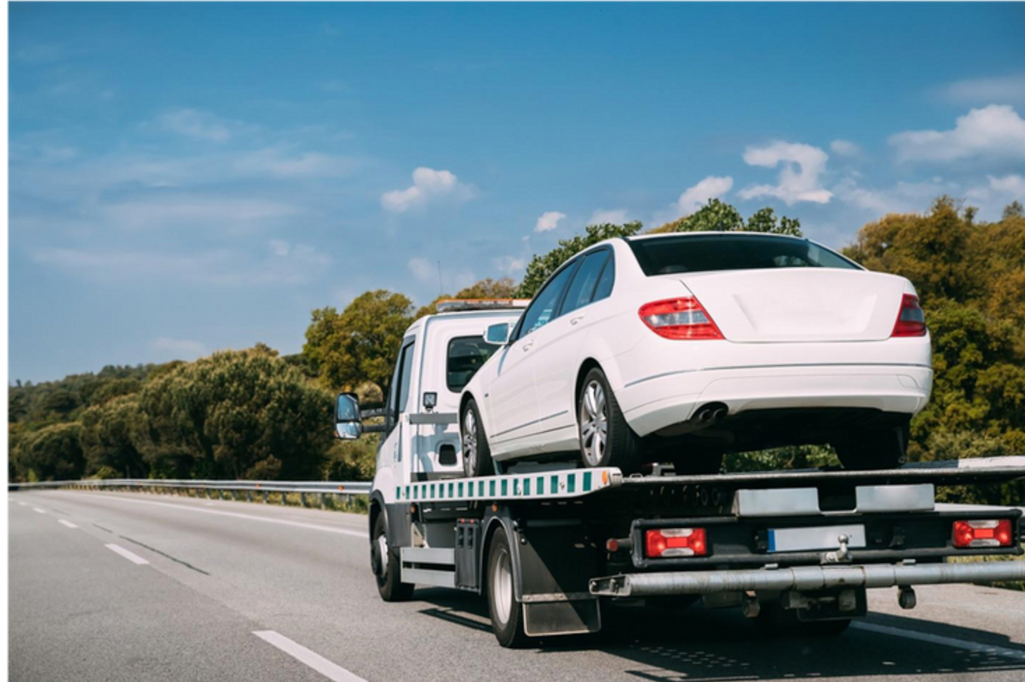 flatbed truck carrying car asset along the motorway