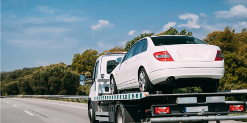 flatbed truck carrying car asset along the motorway
